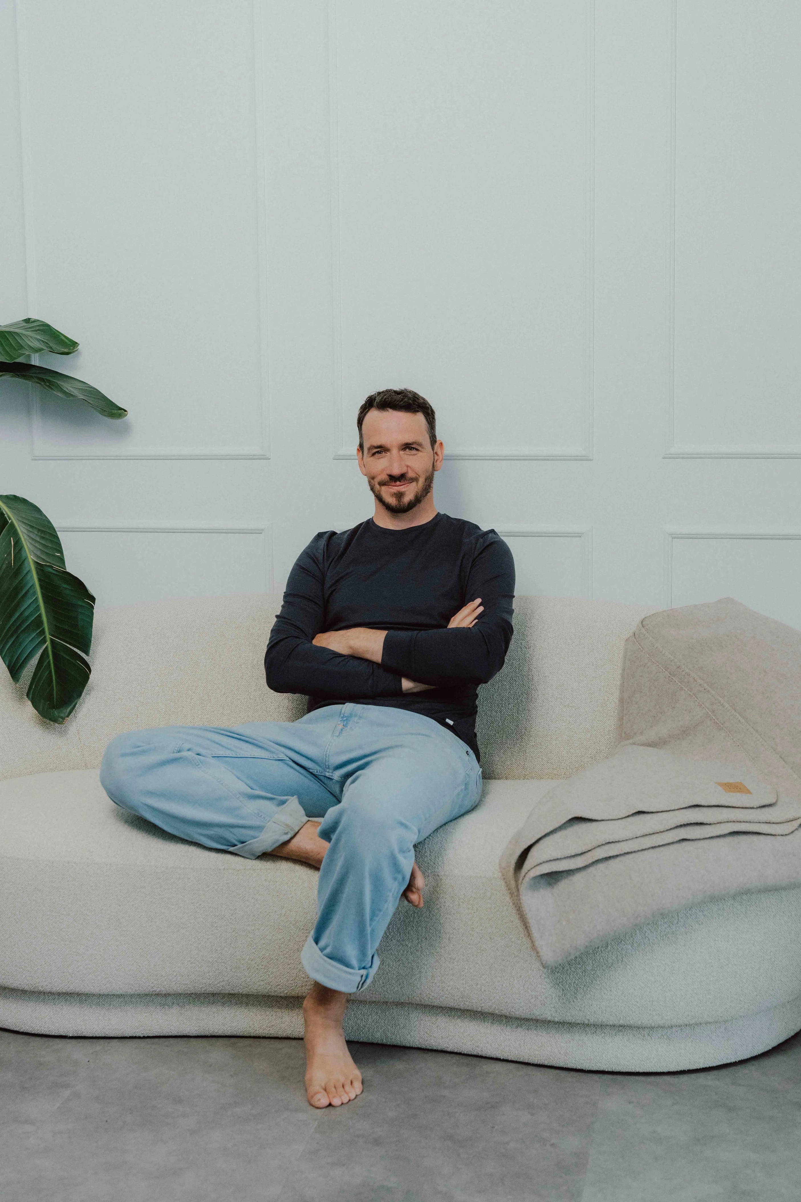 Felix Neureuther im schwarzen TOM FYFE Merino Longsleeve Herren auf hellem Sofa.