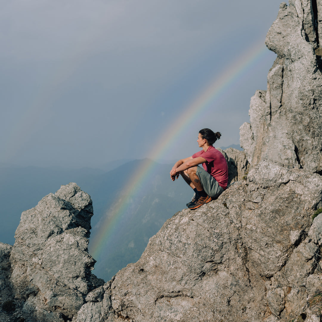 Mann mit Merino Herren T-Shirt von Tom Fyfe blickt ins Tal mit Regenbogen
