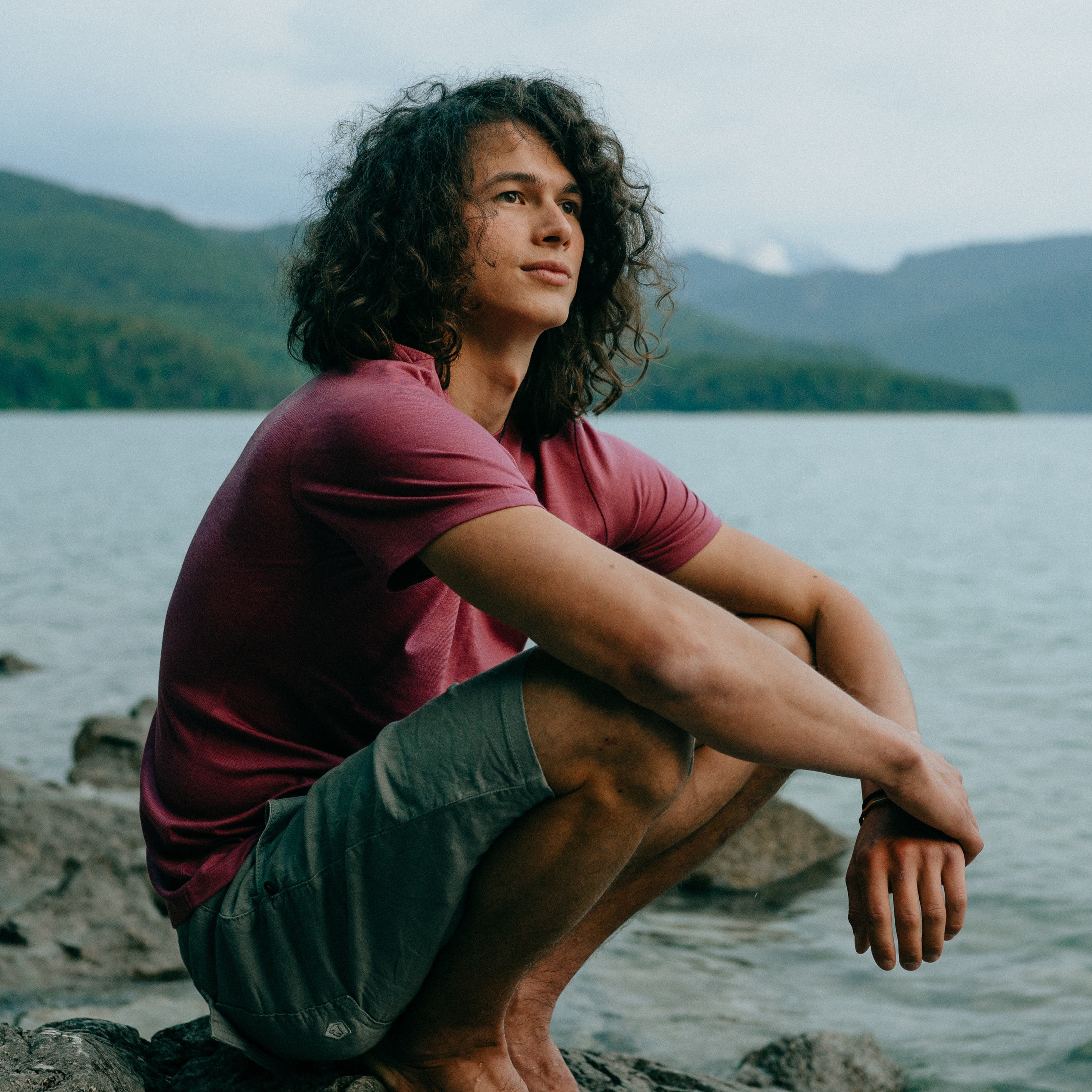 Mann mit Merino T-Shirt von Tom Fyfe am See auf Felsen