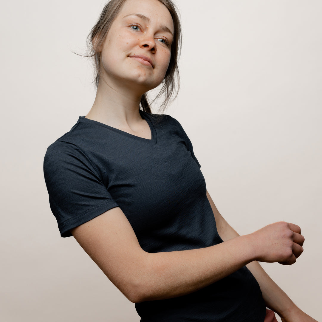 Model mit Merino Damen Shirt mit V-Ausschnitt von Tom Fyfe in Anthrazit Seitenansicht in Bewegung #farbe_anthrazit