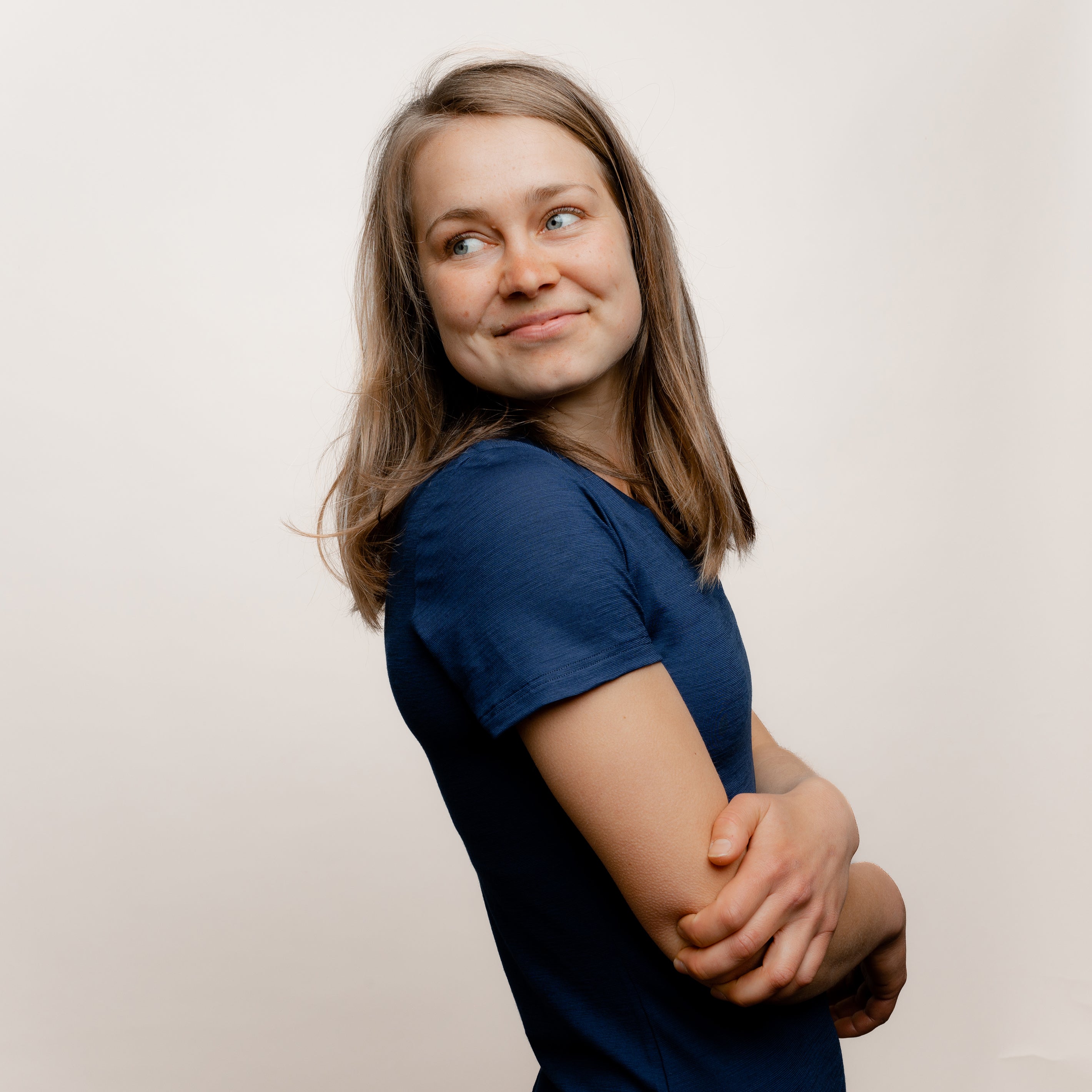 Model mit Merino Damen Shirt mit V-Ausschnitt von Tom Fyfe in Marine Seitenansicht mit verschränkten Armen