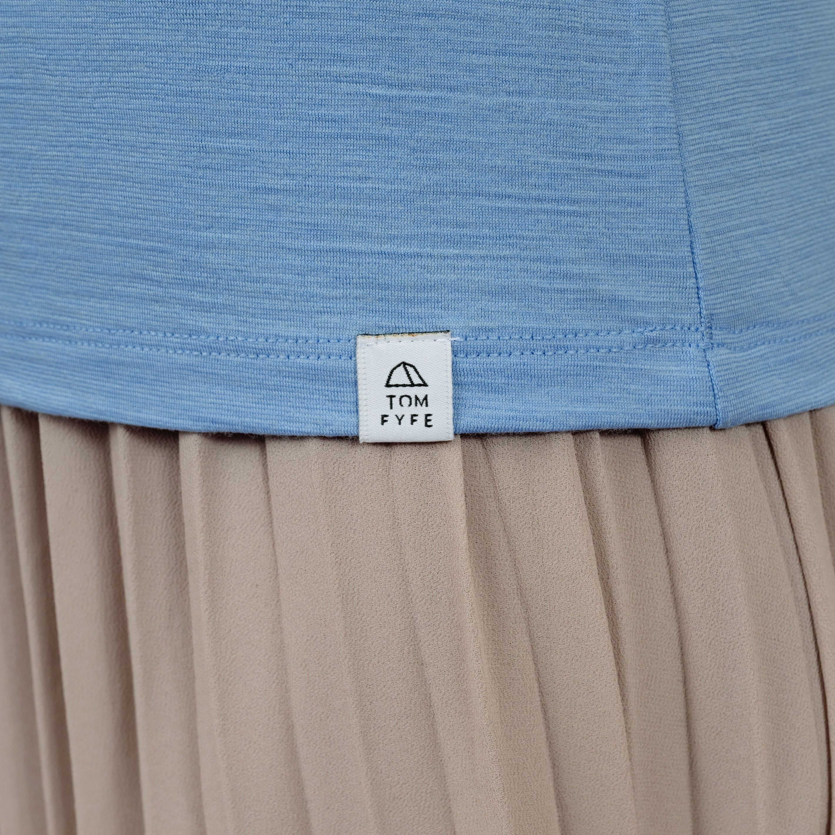 Model mit Merino Damen Shirt mit V-Ausschnitt von Tom Fyfe Saum mit angenähtem Logo in Steelblue