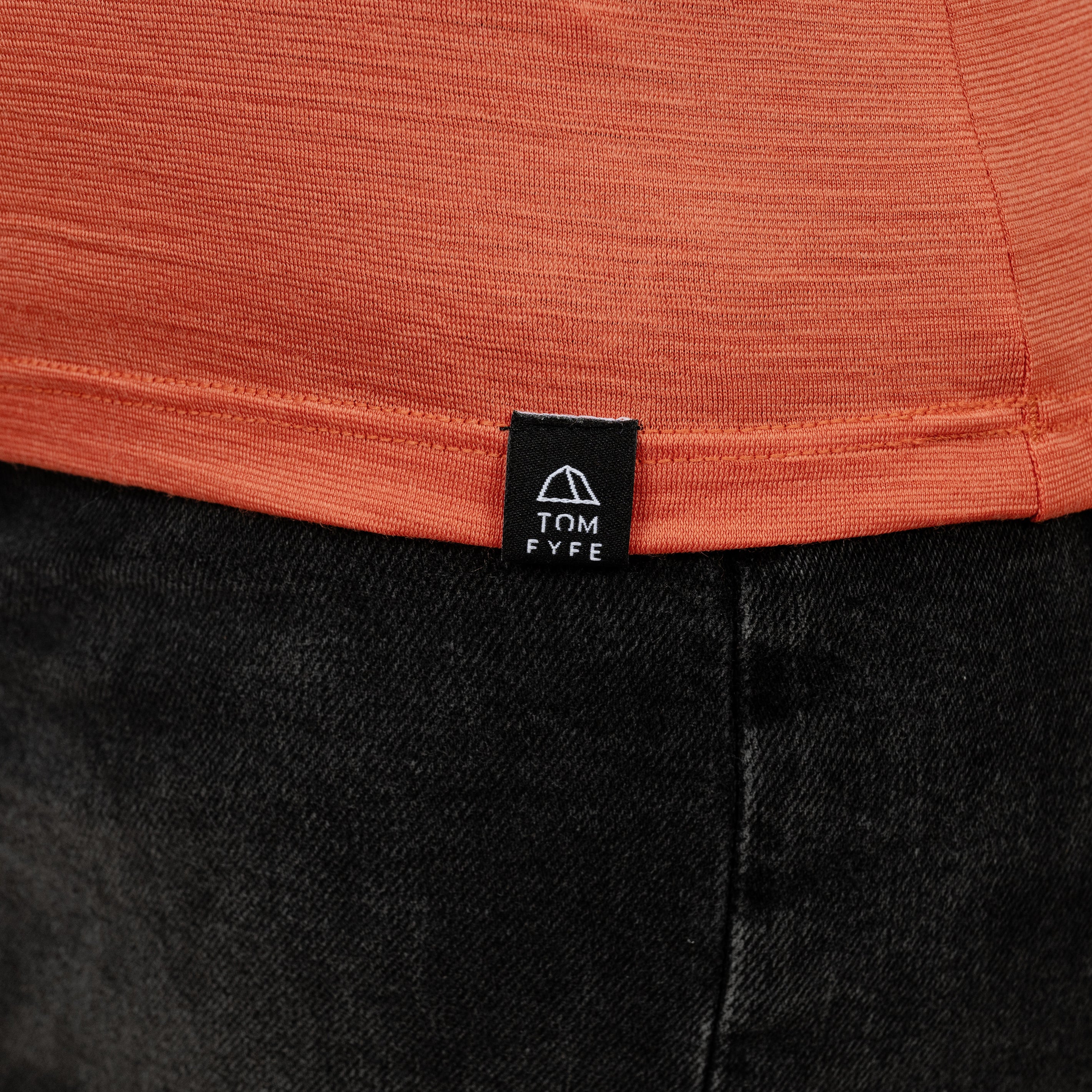 Model mit Merino Damen Shirt mit V-Ausschnitt von Tom Fyfe Saum mit angenähtem Logo in Terracotta