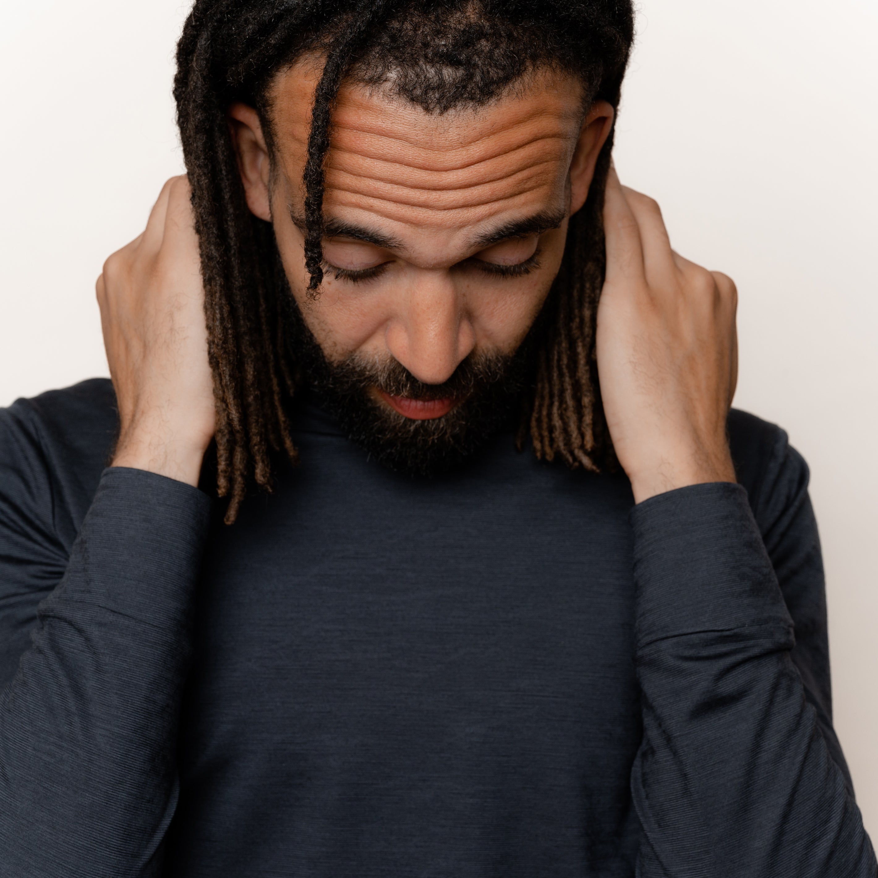 Maennliches Model greift in den Nacken seines Merino Herren Longsleeve von TOM FYFE in Anthrazit