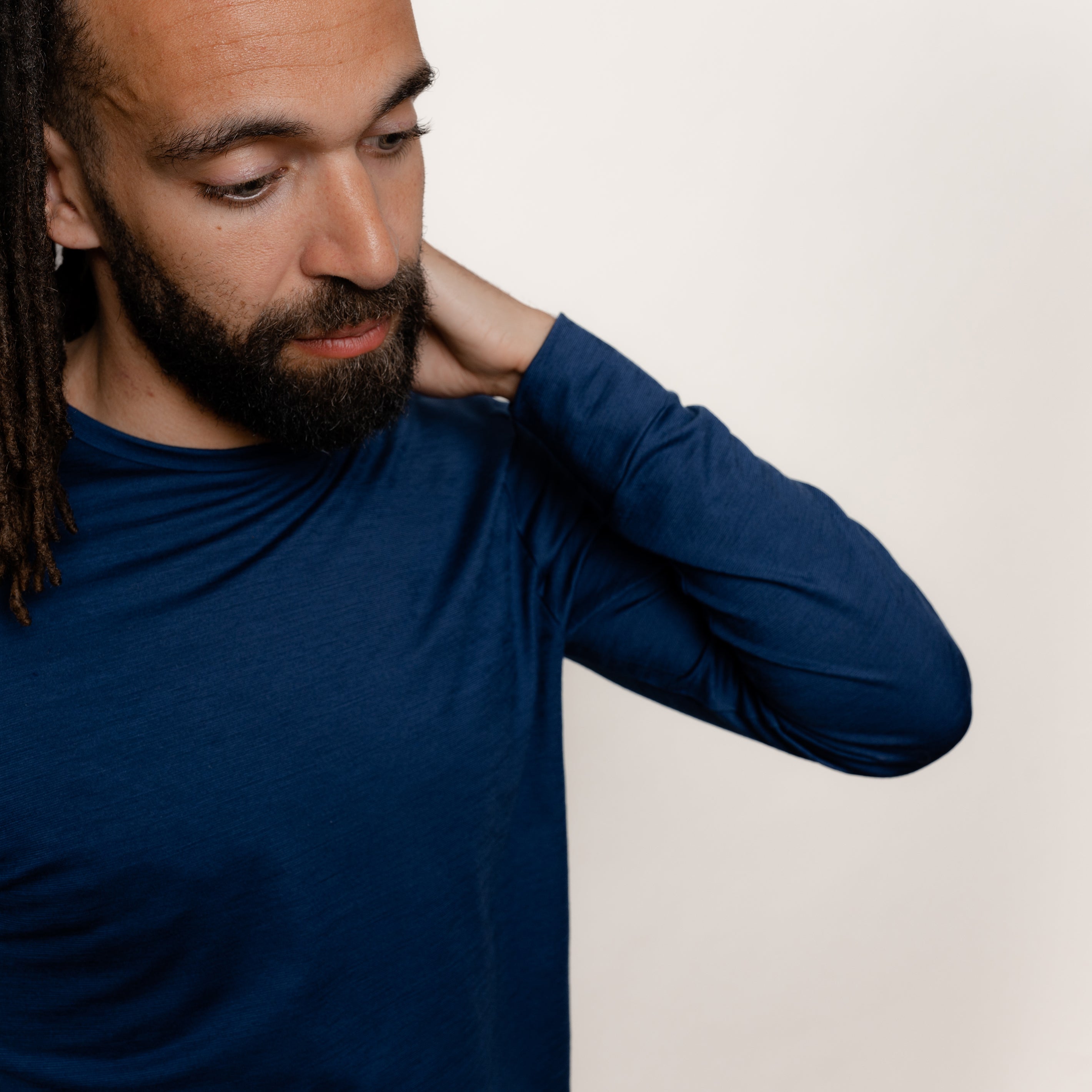 Maennliches Model greift in den Nacken seines Merino Herren Longsleeve von TOM FYFE in Marine