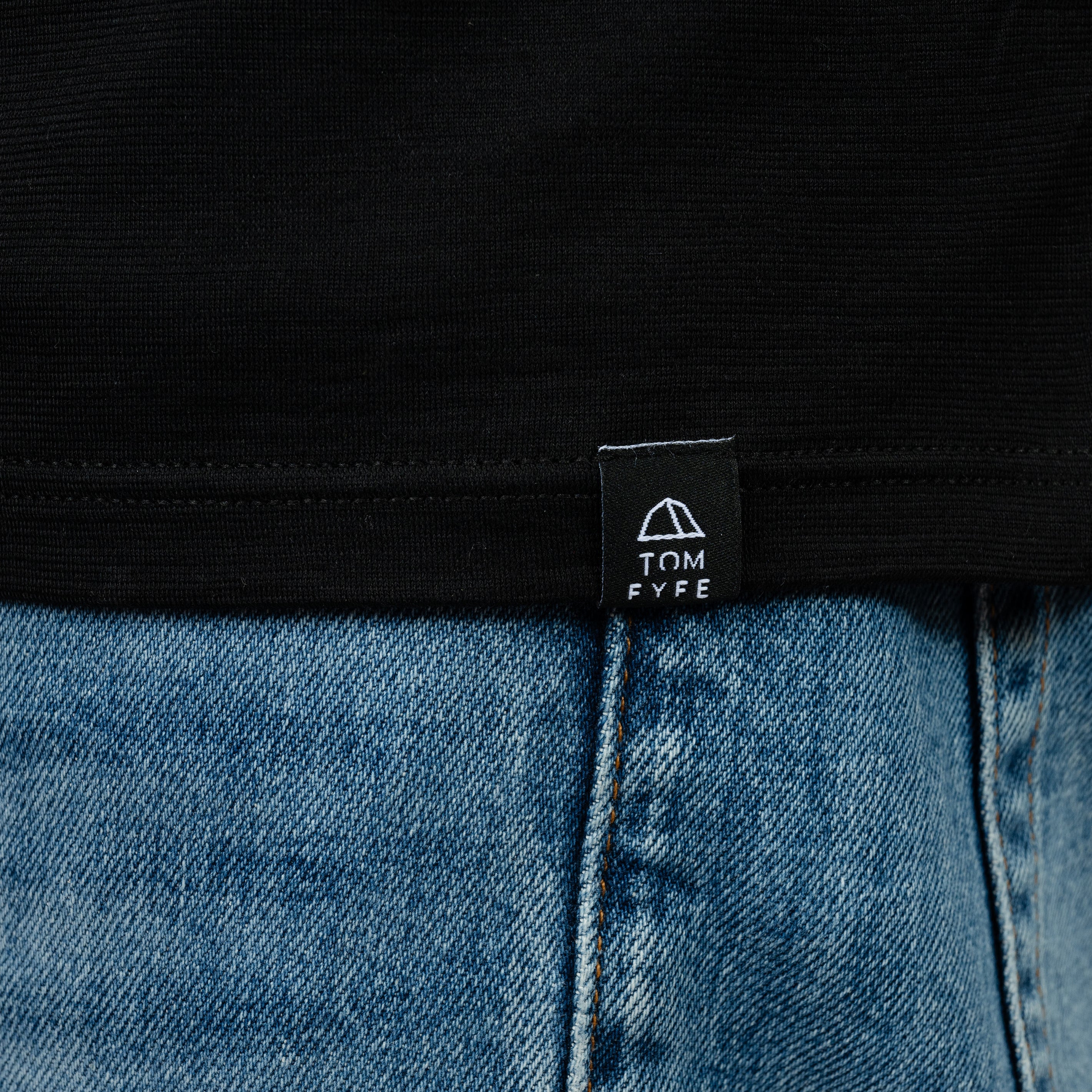 Model mit Merino Herren Poloshirt Label von Tom Fyfe in Schwarz