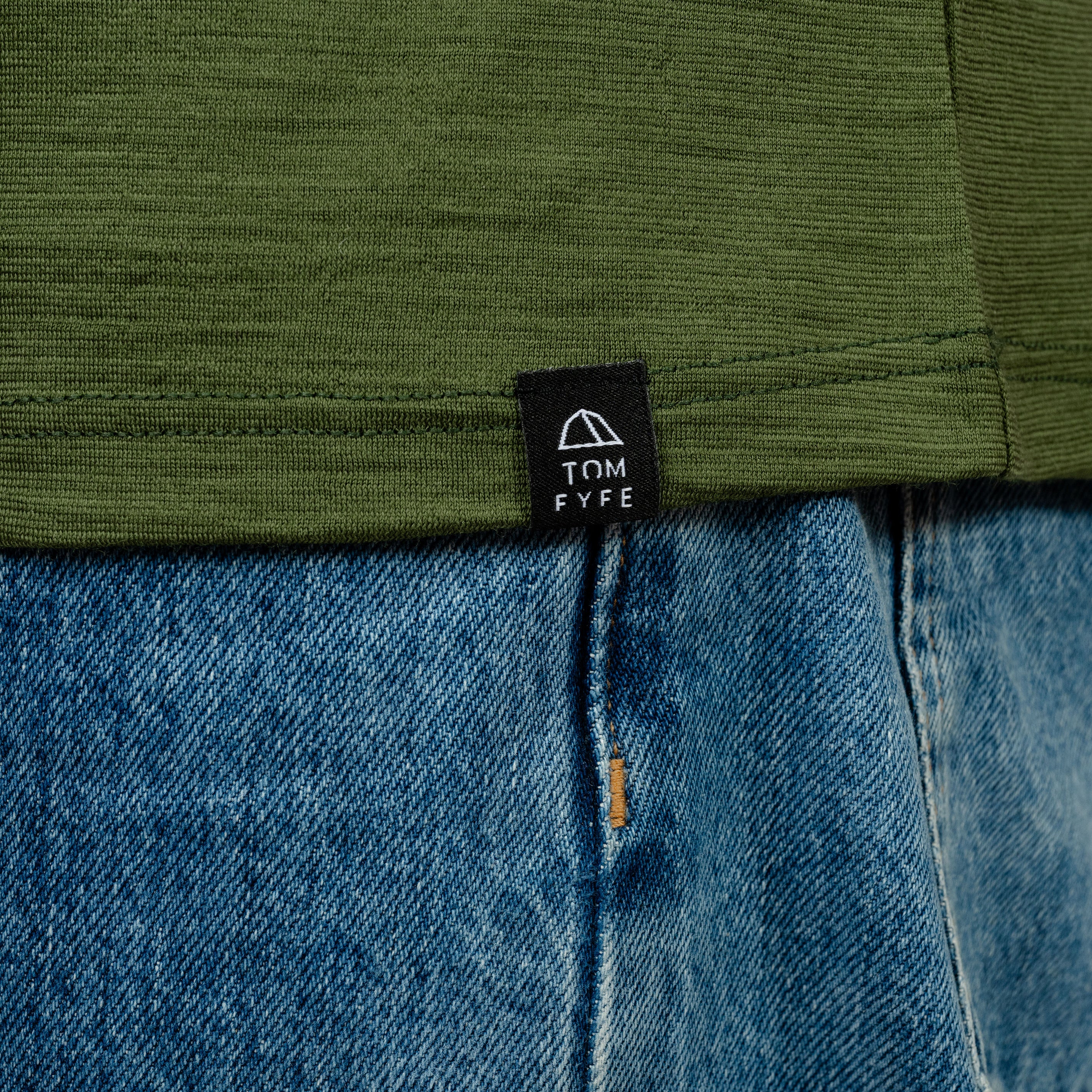 Model mit Merino Herren Shirt mit angenaehtem Stofflabel mit Logo von Tom Fyfe in Waldgrün