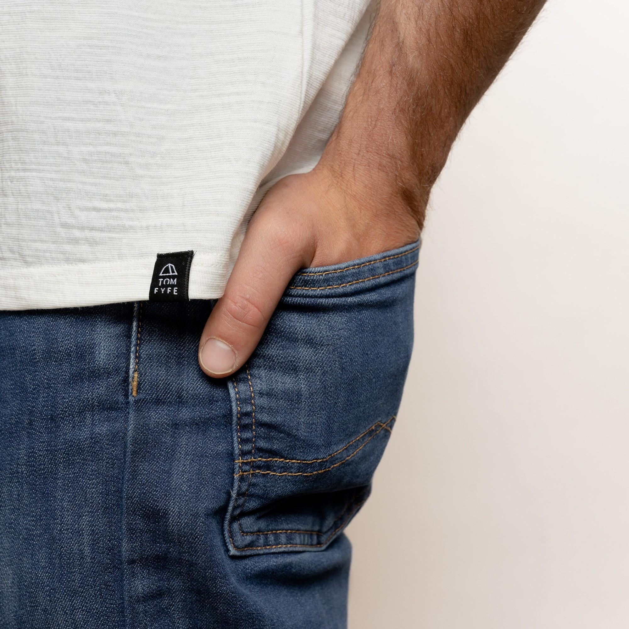 Model mit Merino Herren Shirt mit angenaehtem Stofflabel mit Logo von TOM FYFE in Weiss