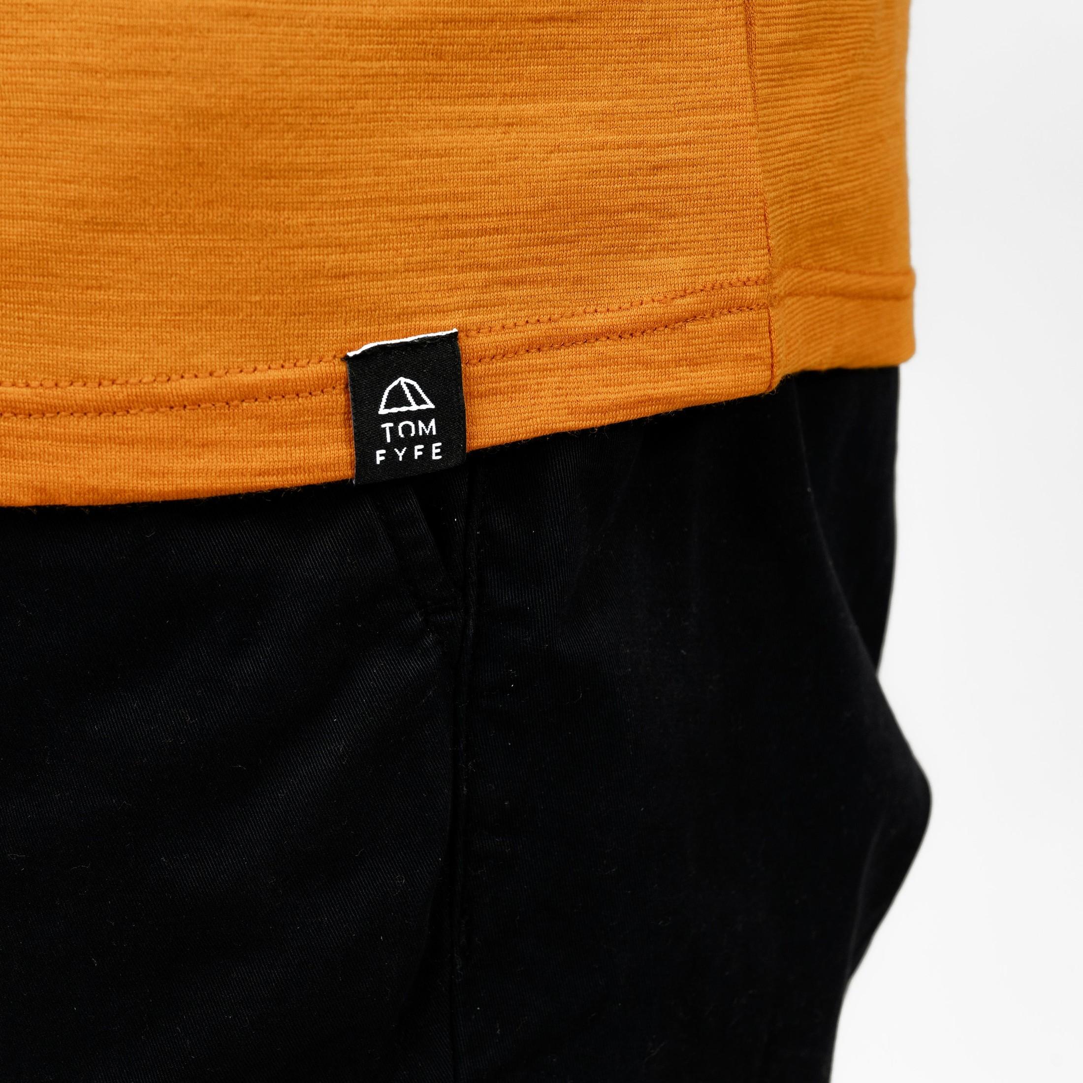 Model mit Merino T-Shirt Regular Fit Unisex mit angenaehtem Stofflabel mit Logo von TOM FYFE in Kurkuma