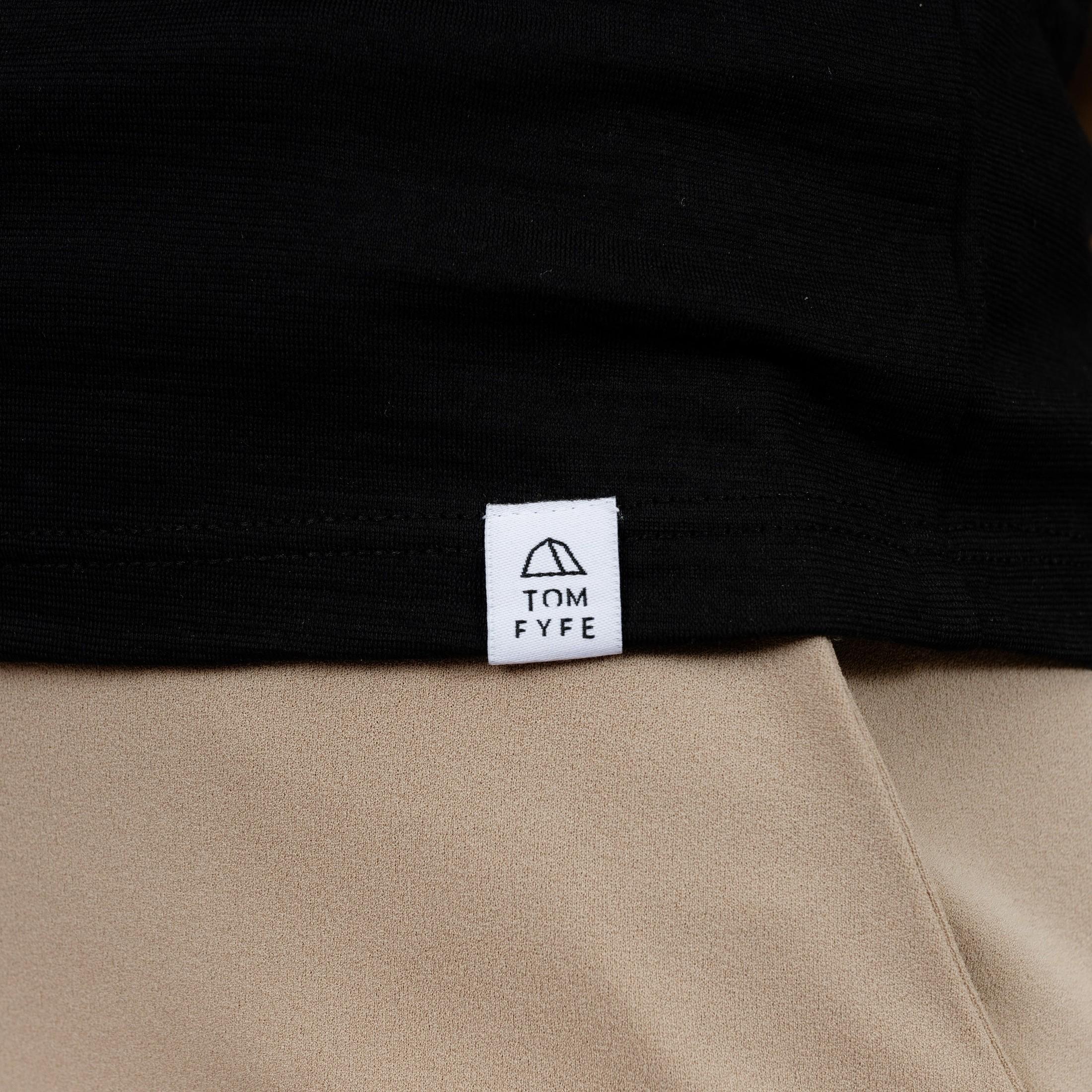 Model mit Merino T-Shirt Regular Fit Unisex mit angenaehtem Stofflabel mit Logo von TOM FYFE in Schwarz