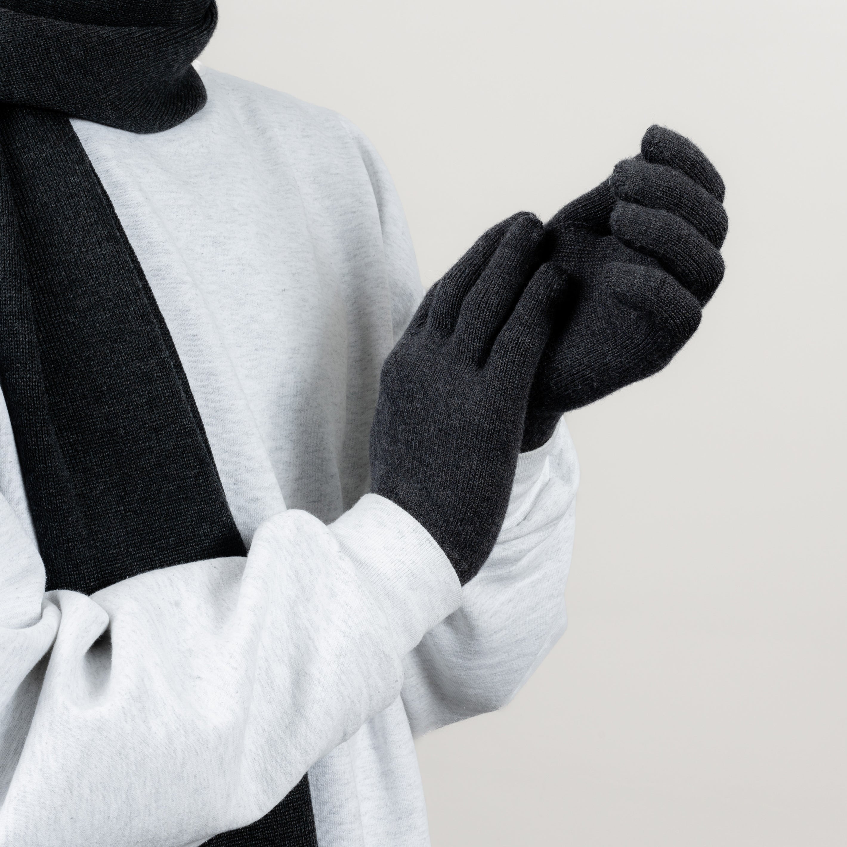 Model trägt Strickhandschuhe aus 90 % Merinowolle von Tom Fyfe in der Farbe Anthrazit