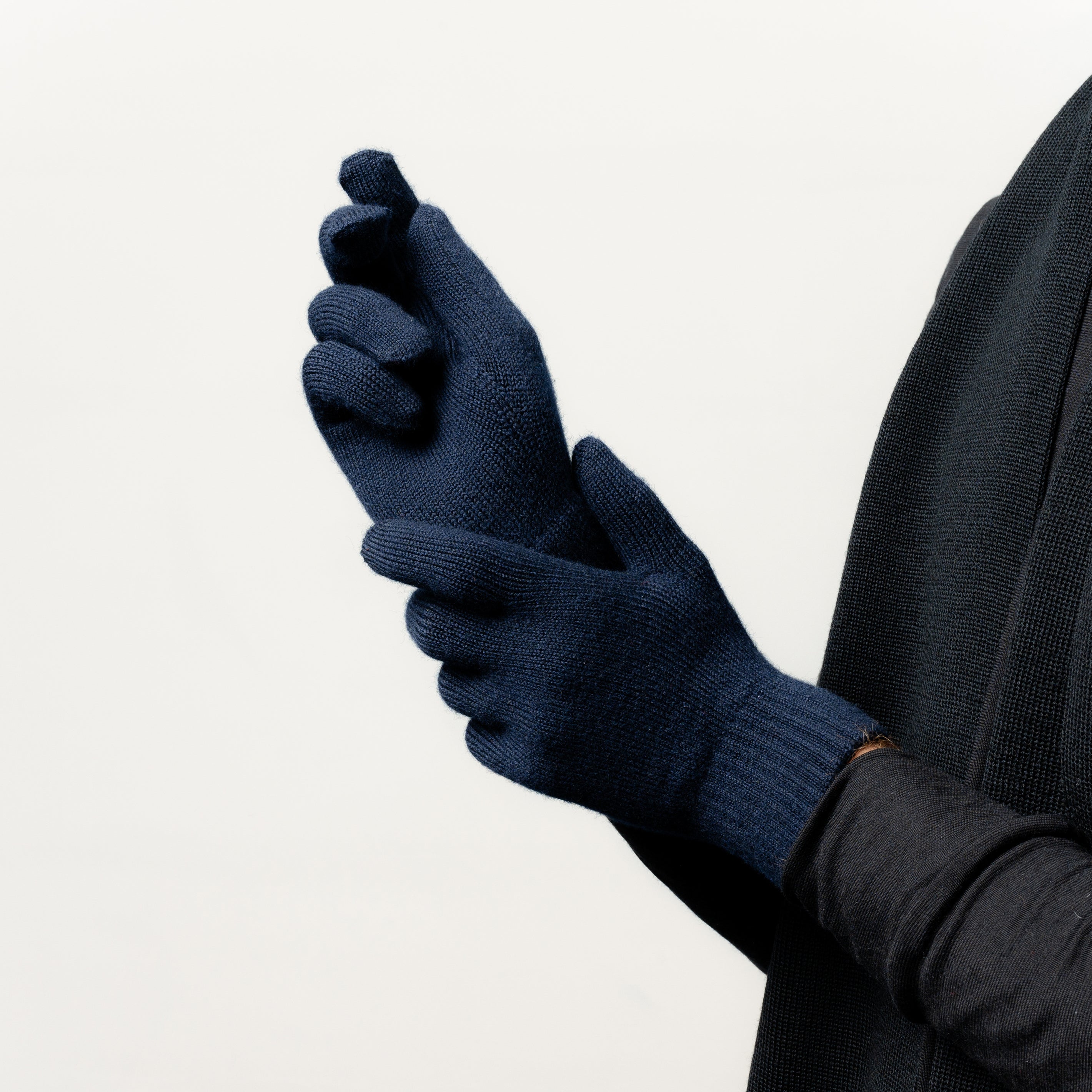 Model trägt Strickhandschuhe aus 90 % Merinowolle von Tom Fyfe in der Farbe Dunkelblau