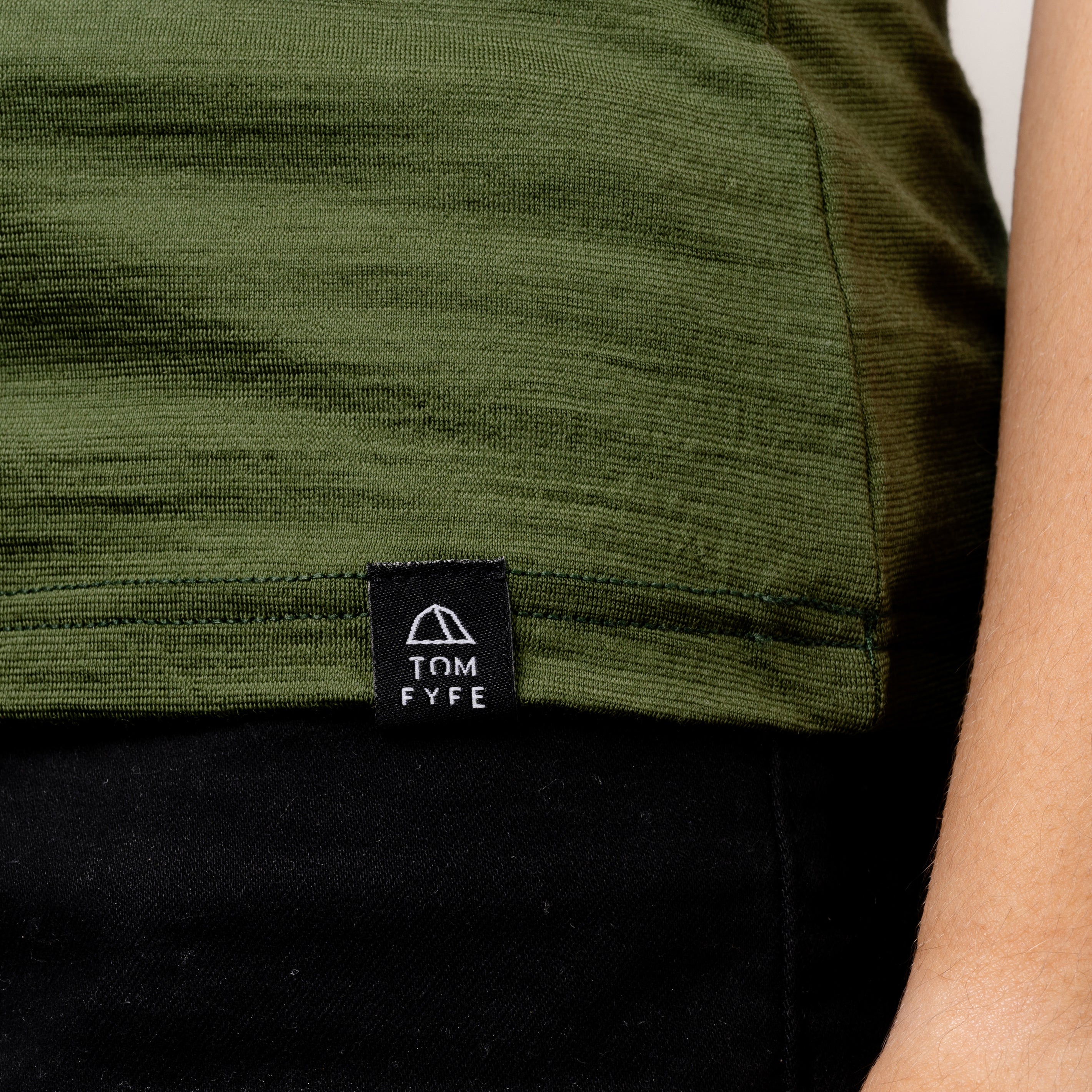 Model im Merino Damen Shirt mit Ausschnitt von Tom Fyfe in Wadgrün Saum mit angenähtem Logo