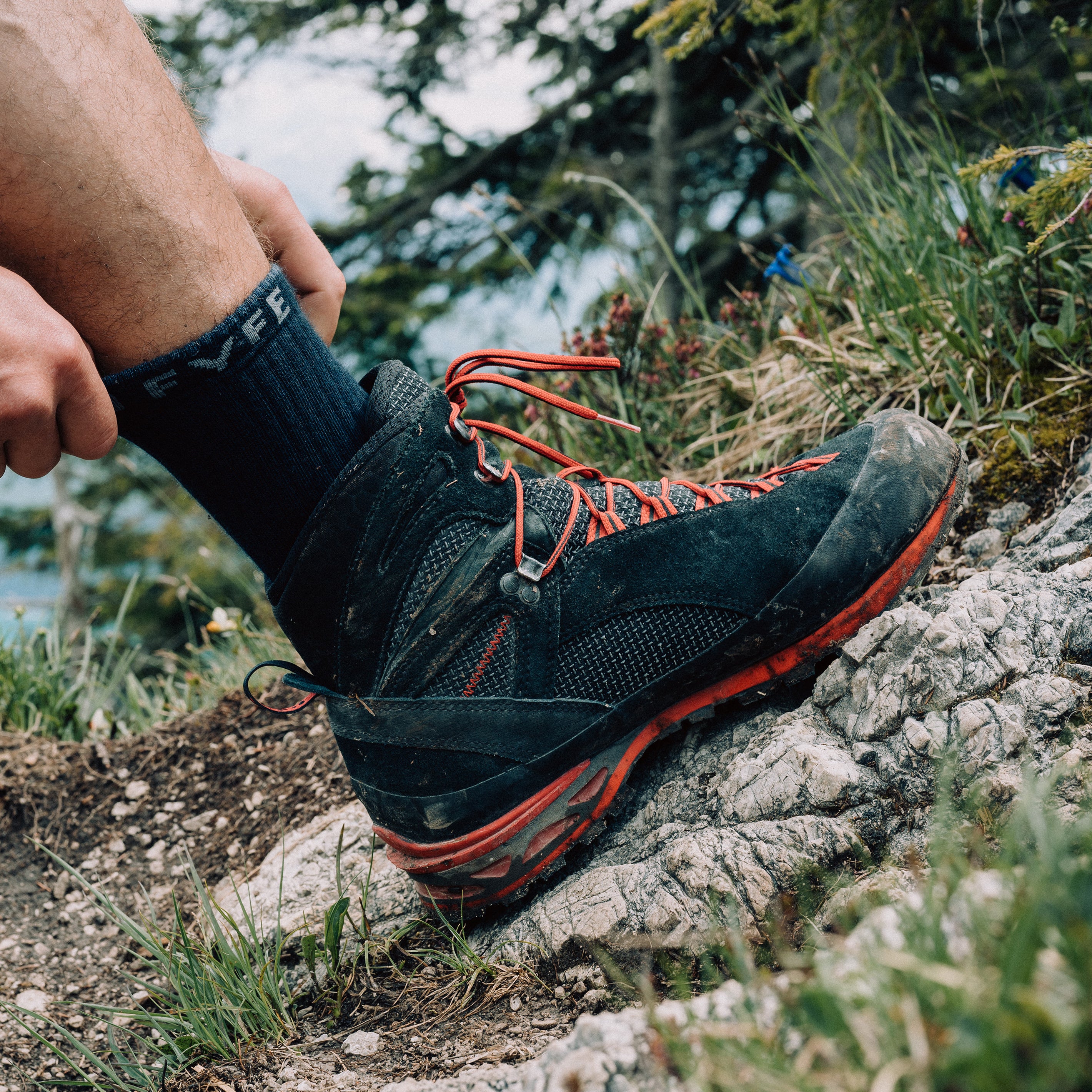 Wanderer trägt Wandersocken aus Merinowolle von Tom Fyfe und läuft einen steinigen Hang entlang