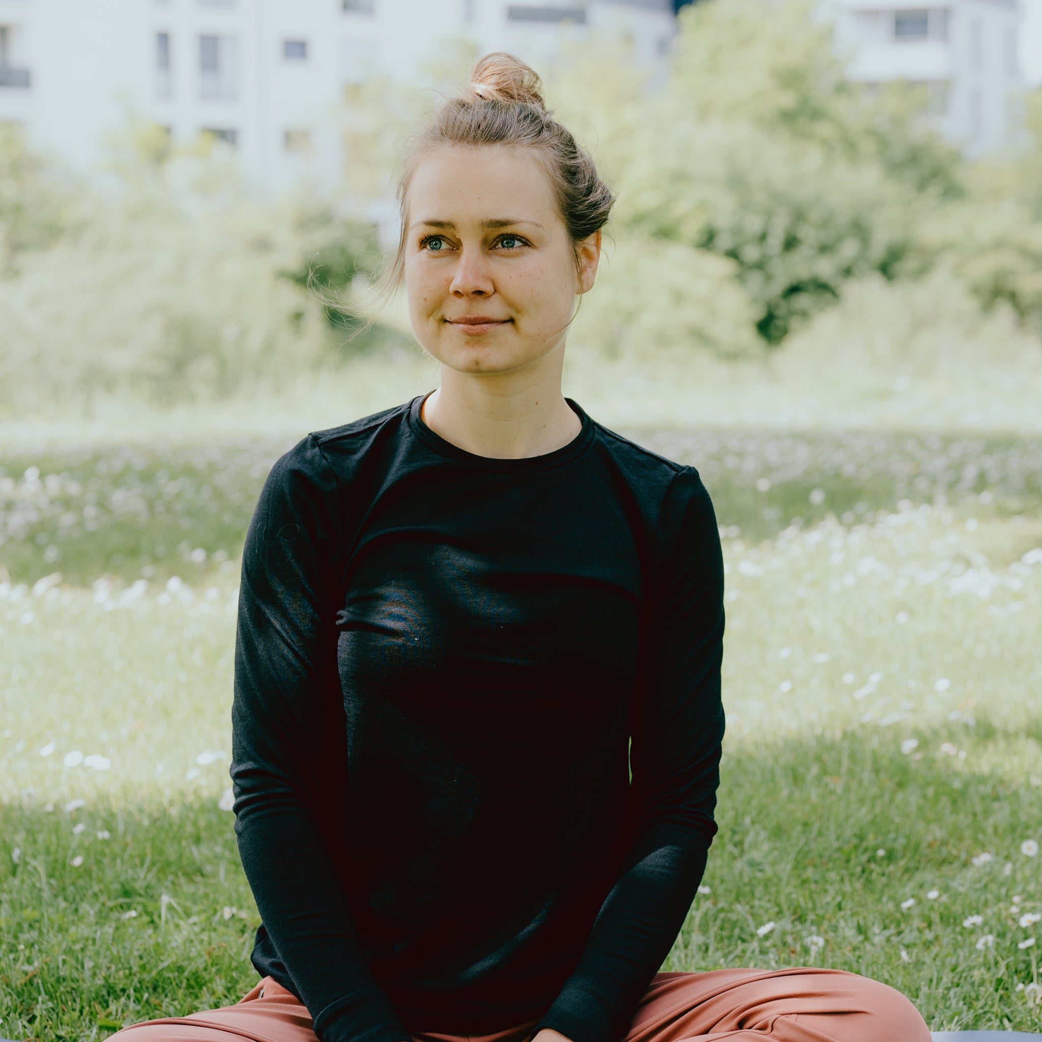 Frau sitzt im Park mit einem Langarmshirt aus Merinowlle von Tom Fyfe