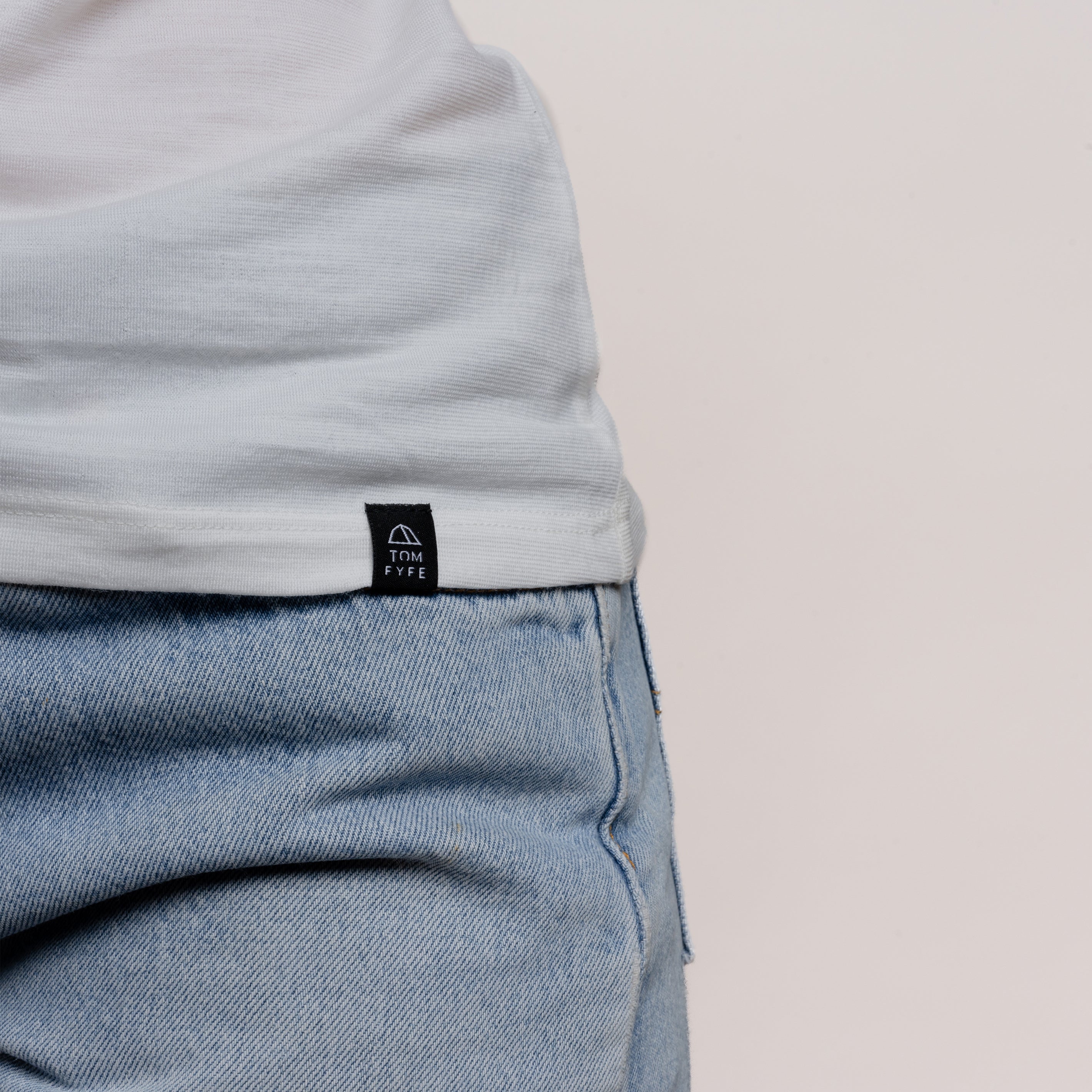 Model mit Merino Damen Shirt mit angenaehtem Stofflabel mit Logo von Tom Fyfe in Weiss
