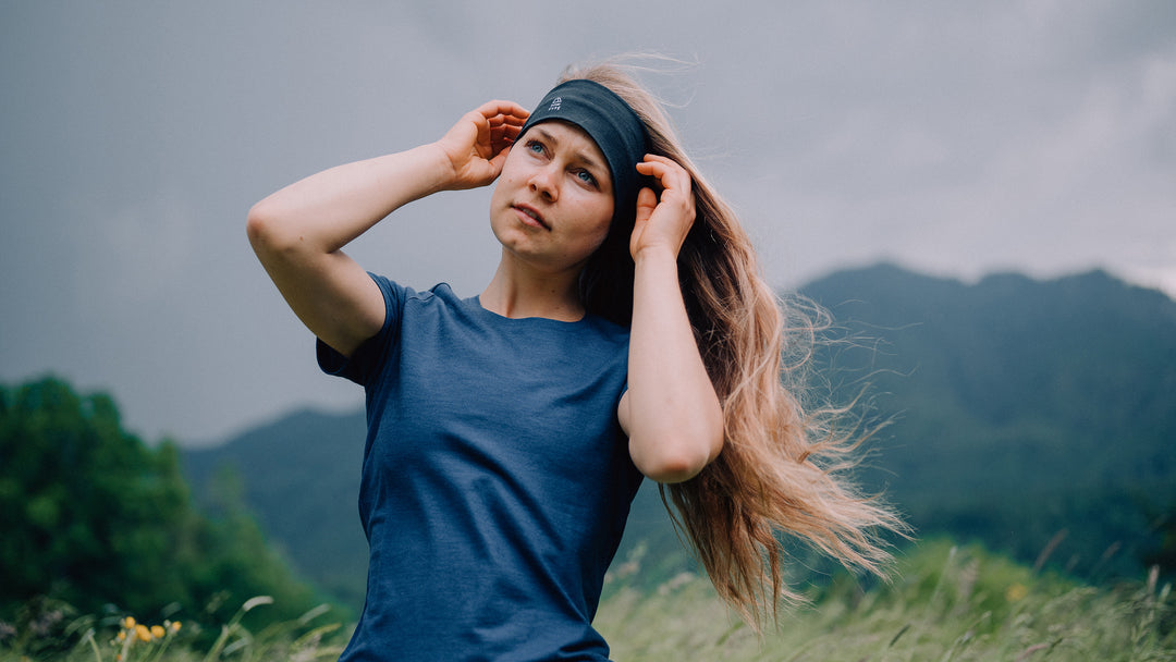 Frau steht im Wind auf Wiese mit Merino Stirnband und T-Shirt von Tom Fyfe
