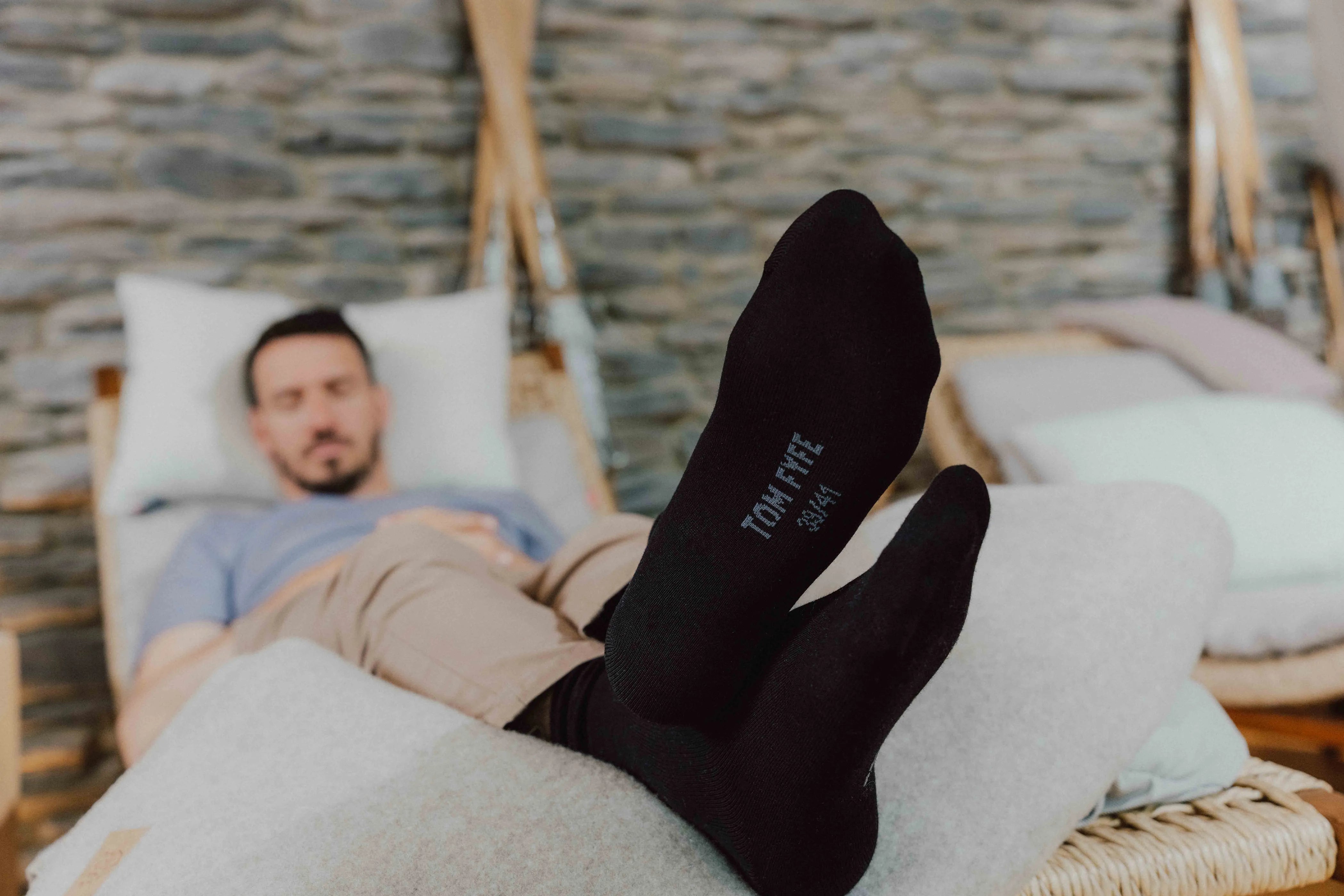 Felix Neureuther entspannt in schwarzen TOM FYFE Merino Socken auf einer Liege.