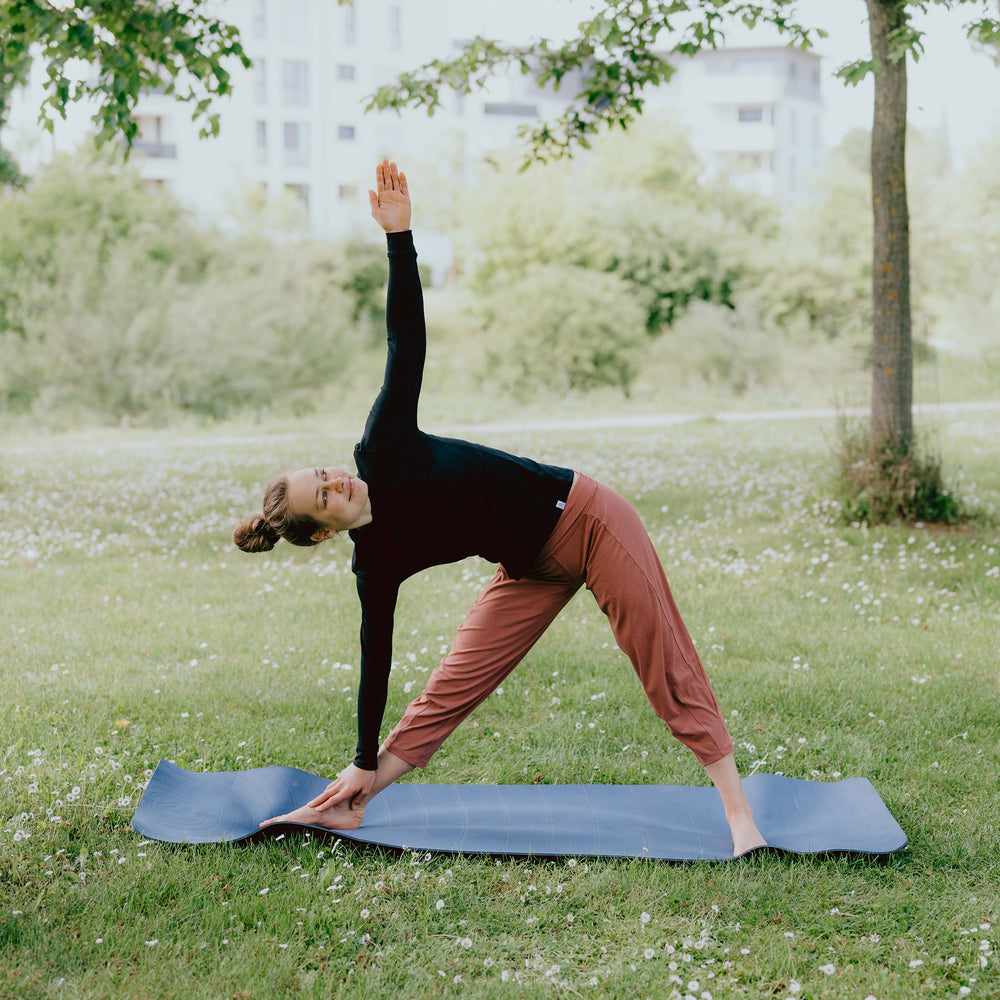 Frau macht Yoga im Park mit einem Merino-Langarmshirt #farbe_schwarz