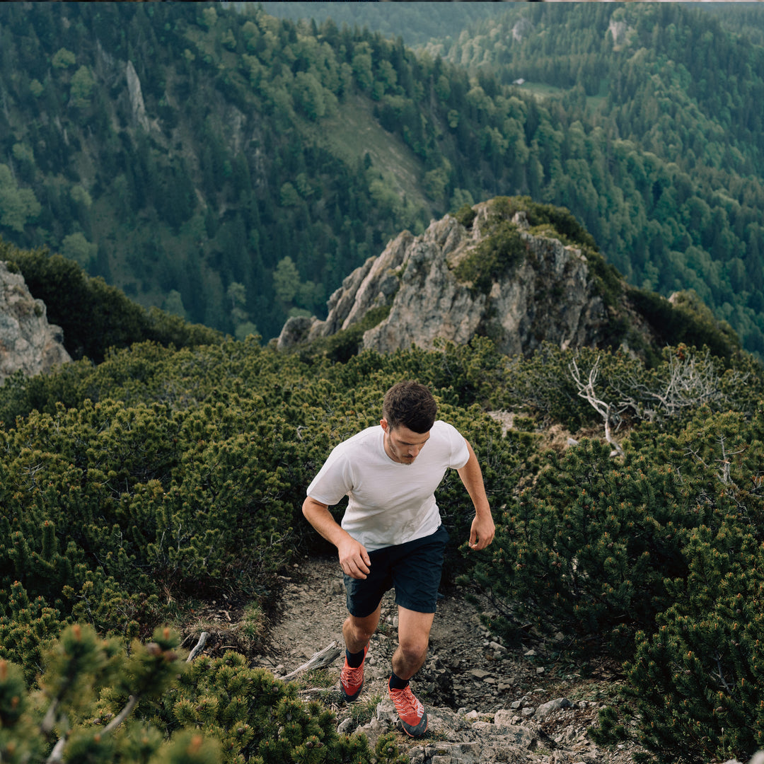Mann läuft Berg hinauf mit Merino T-Shirt in Weiss von Tom Fyfe