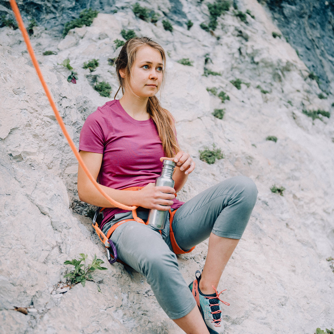 Frau sitzt auf dem Fels beim Klettereinstieg und trägt ein T-shirt aus Merinowolle von Tom Fyfe #farbe_anthrazit