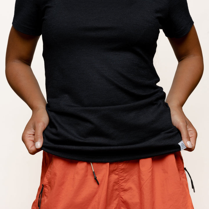 Model mit Merino Damen Shirt mit angenaehtem Stofflabel mit Logo von Tom Fyfe in Schwarz #farbe_schwarz