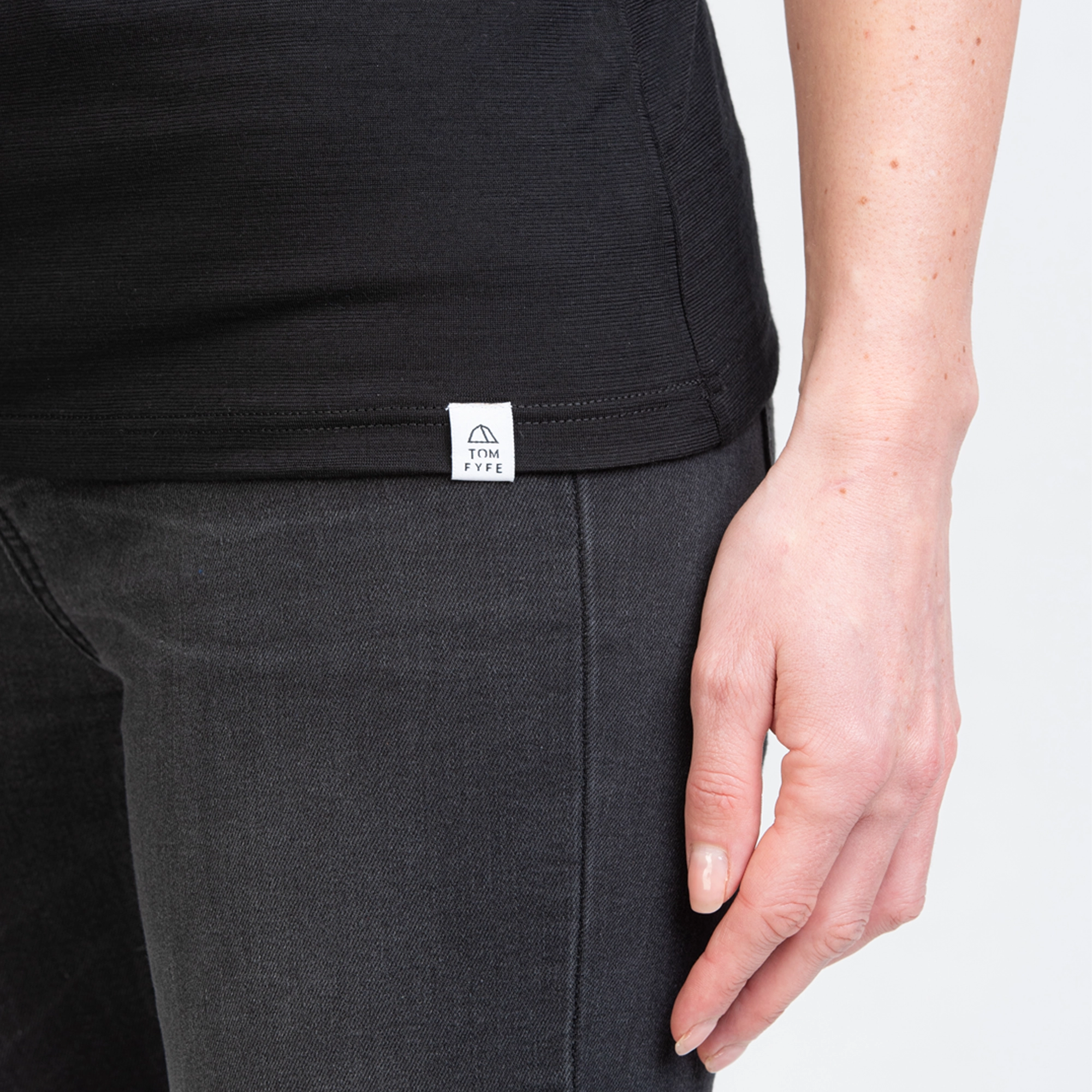 Model mit Merino Damen Shirt mit angenaehtem Stofflabel mit Logo von TOM FYFE in Schwarz 