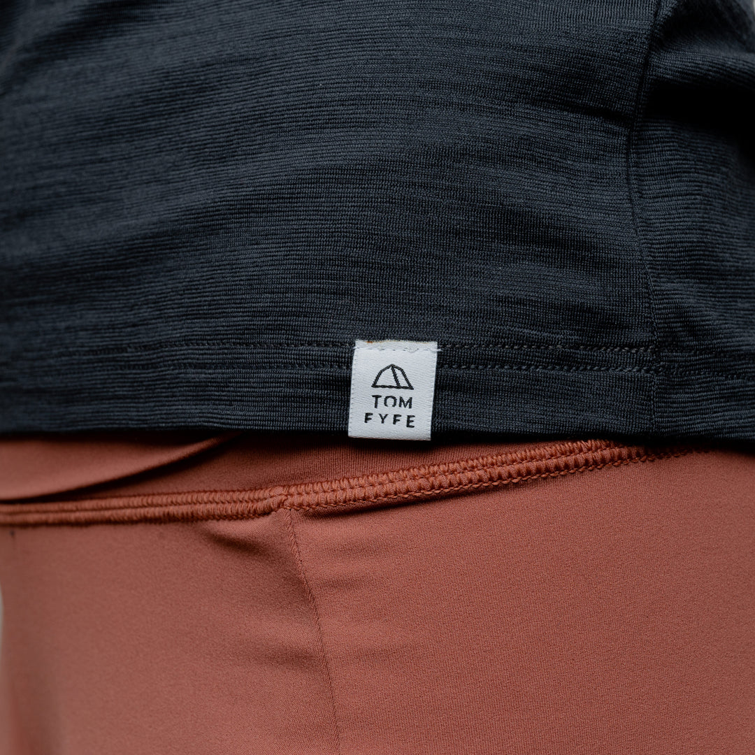 Merino Damen Shirt mit V-Ausschnitt von Tom Fyfe in Anthrazit mit angenähtem Stofflabel mit Logo #farbe_anthrazit