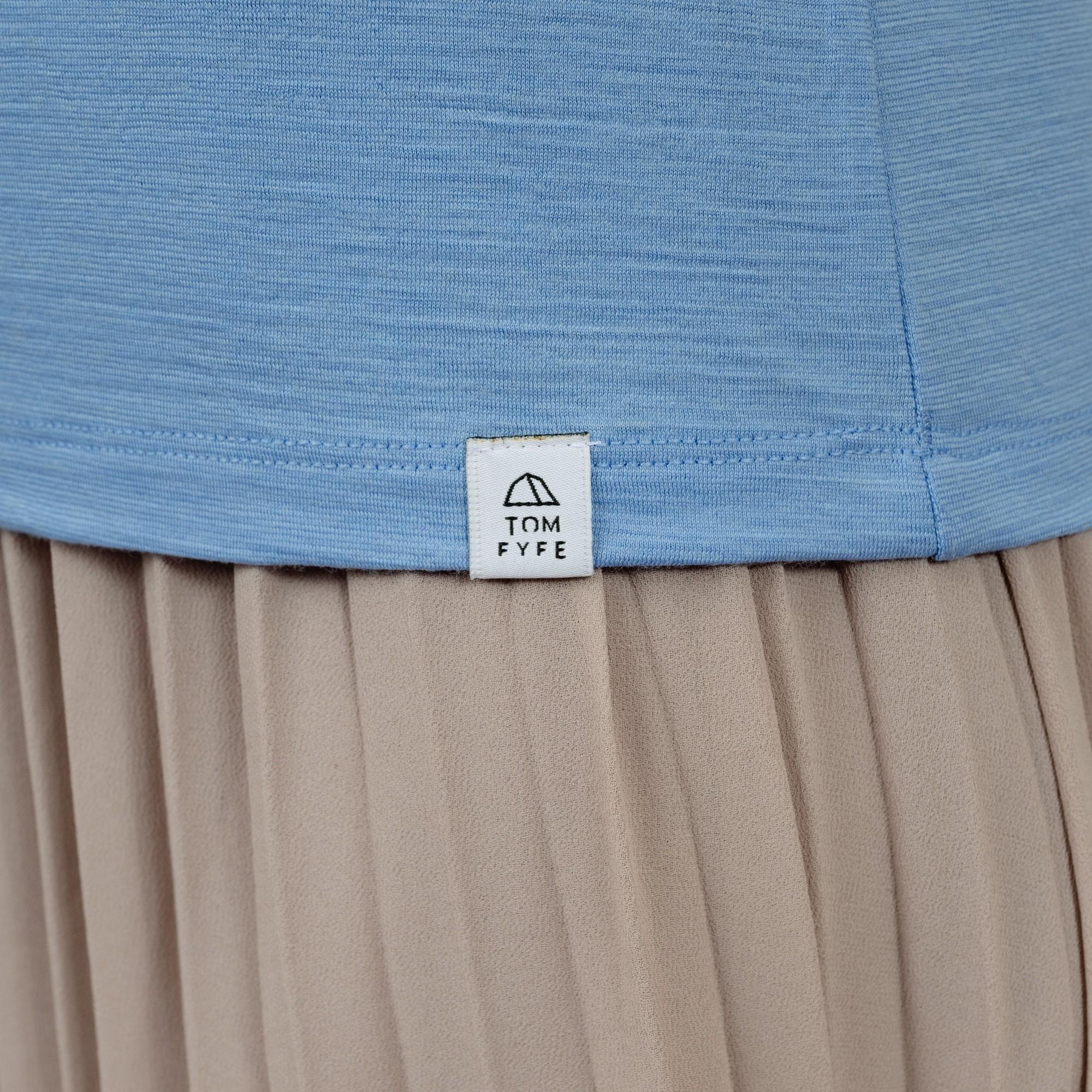 Model mit Merino Damen Shirt mit V-Ausschnitt von Tom Fyfe Saum mit angenähtem Logo in Steelblue 
