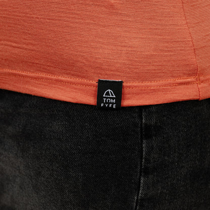 Model mit Merino Damen Shirt mit V-Ausschnitt von Tom Fyfe Saum mit angenähtem Logo in Terracotta 