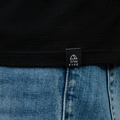 Model mit Merino Herren Poloshirt Label von Tom Fyfe in Schwarz 