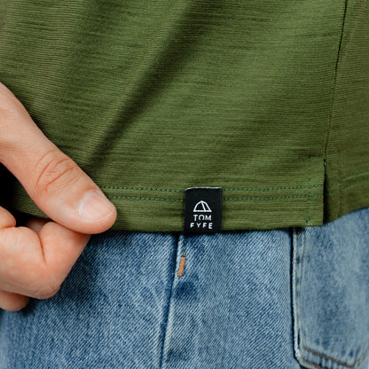 Model mit Merino Herren Poloshirt Label von Tom Fyfe in Waldgruen 
