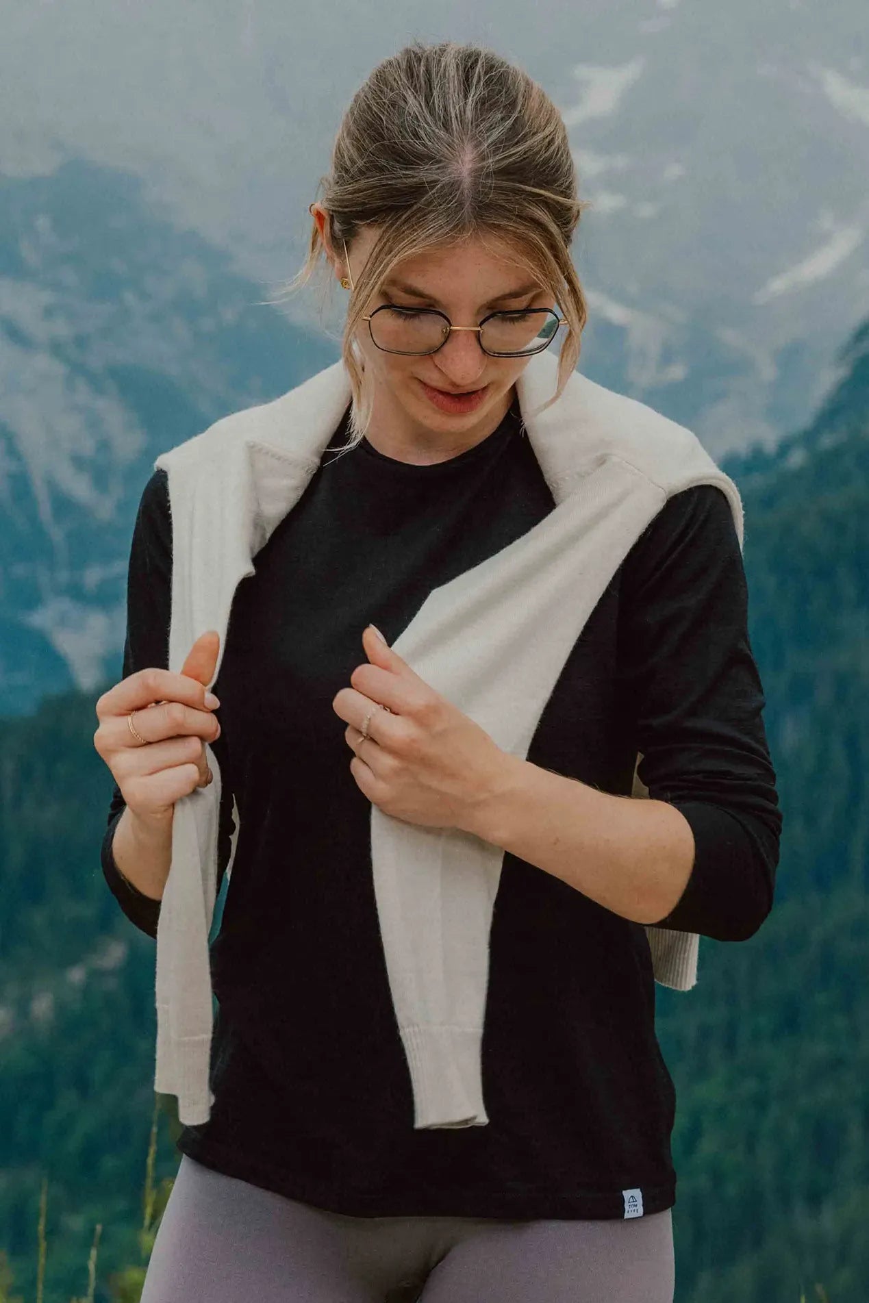 Frau im schwarzen TOM FYFE Merino Longsleeve Damen vor alpiner Berglandschaft.