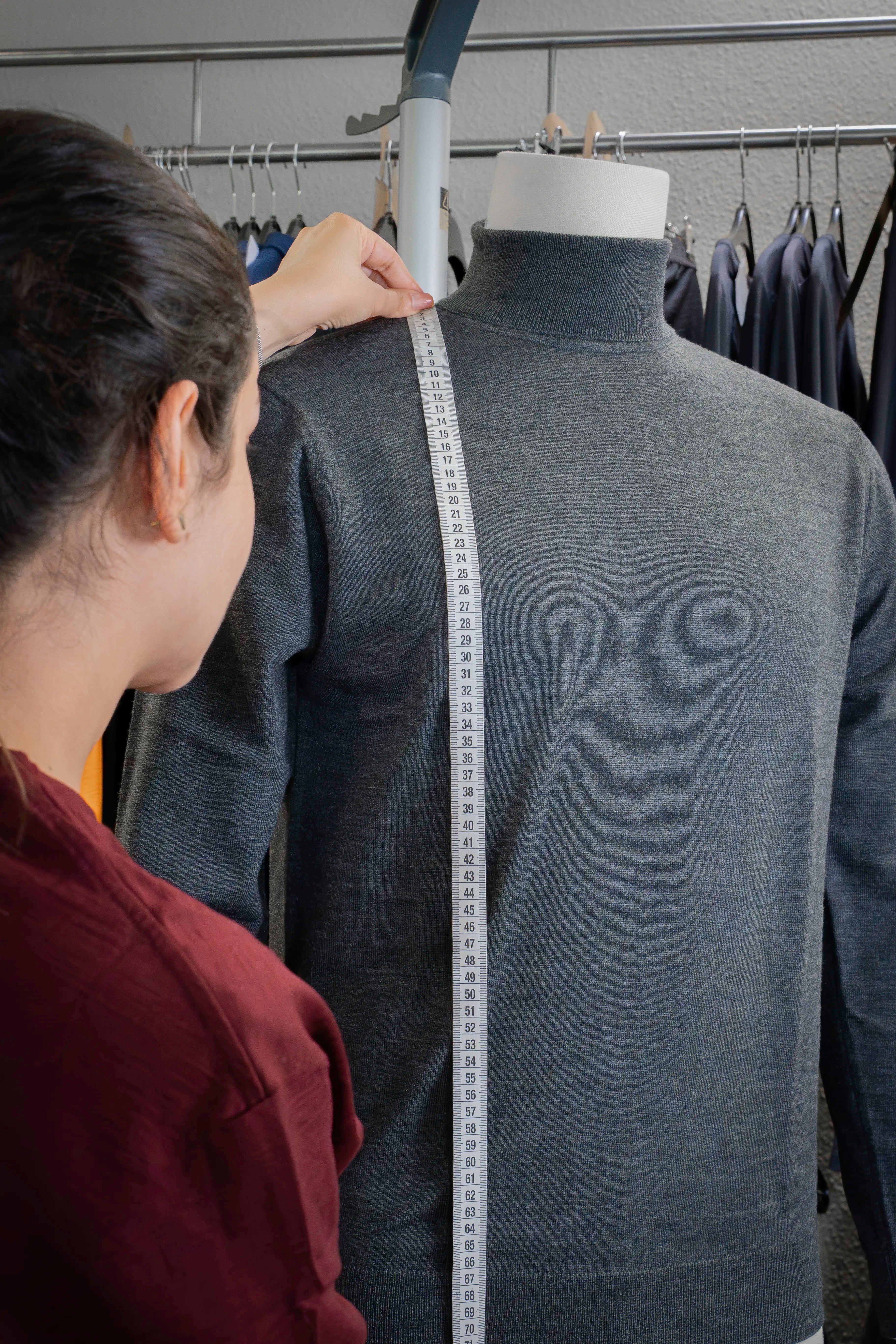 Maßkontrolle an einem grauen TOM FYFE Merino Pullover auf einer Schneiderpuppe.