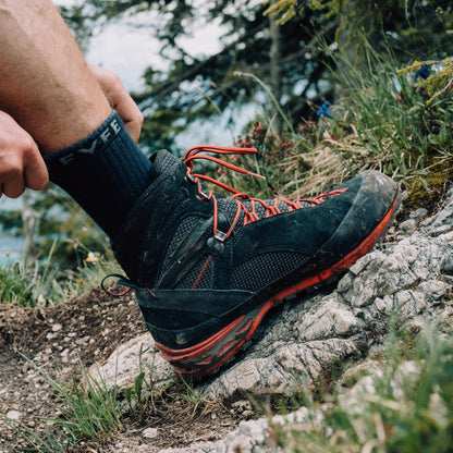 Wanderer trägt Wandersocken aus Merinowolle von Tom Fyfe und läuft einen steinigen Hang entlang 
