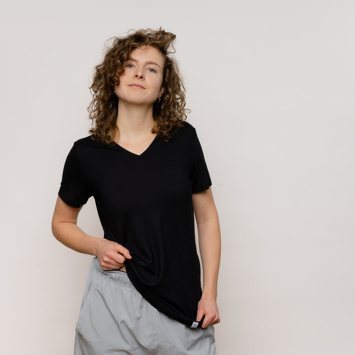 Model mit Merino Damen Shirt mit V-Ausschnitt Frontansicht von Tom Fyfe in Schwarz #farbe_schwarz