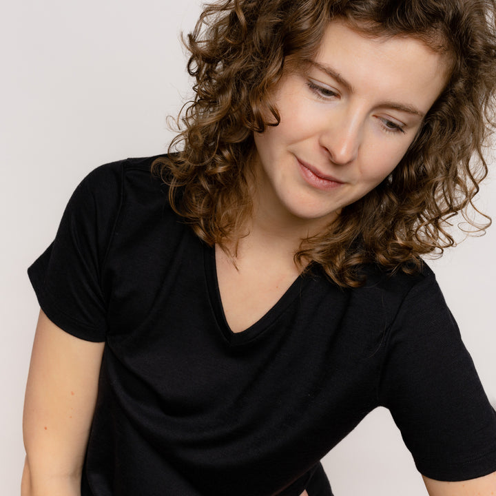 Model mit Merino Damen Shirt mit V-Ausschnitt Nackenbereich von Tom Fyfe in Schwarz #farbe_schwarz