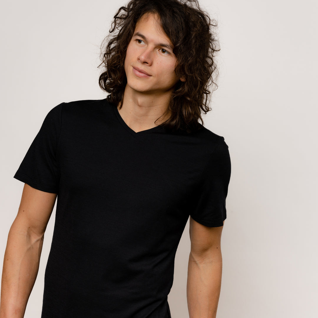 Model mit Merino Herren Shirt mit V-Ausschnitt Frontansicht von Tom Fyfe in Schwarz #farbe_schwarz