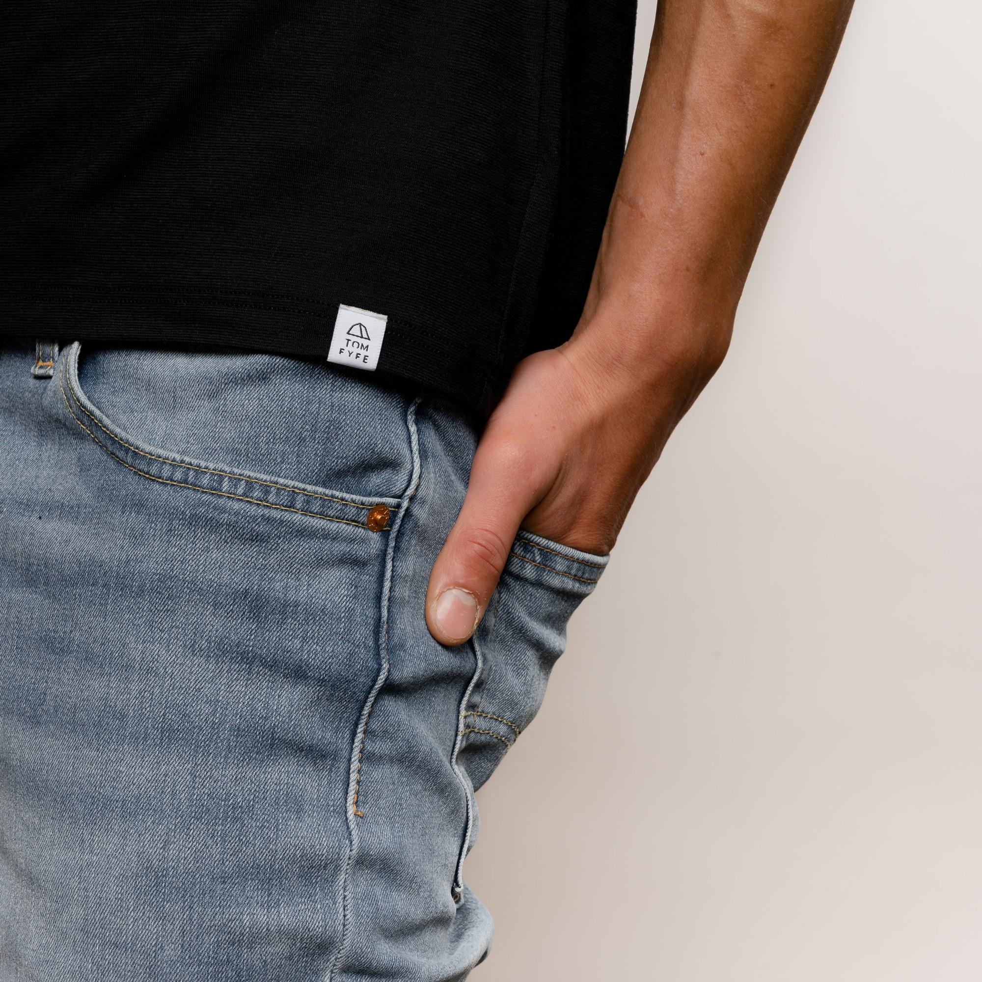 Model mit Merino Herren Tanktop mit angenaehtem Stofflabel mit Logo von Tom Fyfe in Schwarz 